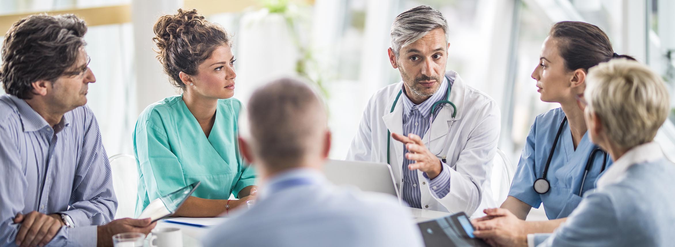 Group of doctors seated around table in discussion.