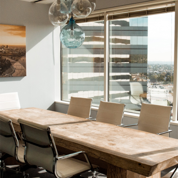 Conference room with large table, office chairs, chandelier, and large windows.